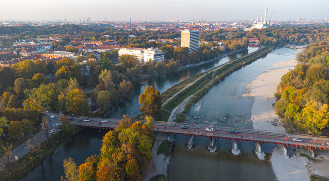 Aerial view of Isar river flowing into Munich and Thalkirchen bridge with cars in a beautiful autumn landscape