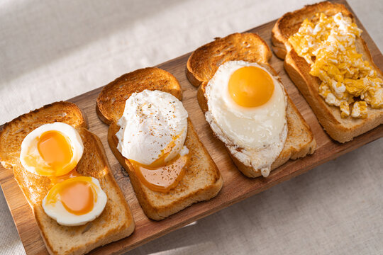 fried Toast bread with four different types of cooked chicken eggs, scrambled eggs, fried eggs, poached egg and creamed egg. Breakfast of chicken eggs. methods of making eggs for breakfast