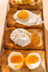 fried Toast bread with four different types of cooked chicken eggs, scrambled eggs, fried eggs, poached egg and creamed egg. Breakfast of chicken eggs. methods of making eggs for breakfast