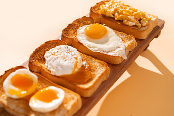 fried Toast bread with four different types of cooked chicken eggs, scrambled eggs, fried eggs, poached egg and creamed egg. Breakfast of chicken eggs. methods of making eggs for breakfast