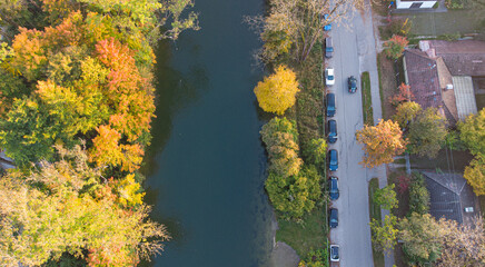 Top view of a street in Germany in autumn with colorful trees. Aerial drone perspective of Isar...