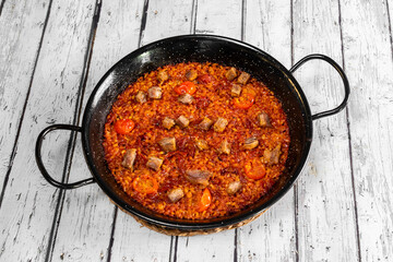 Tomato paella and Iberian secret with socarrat rice on black paella pan