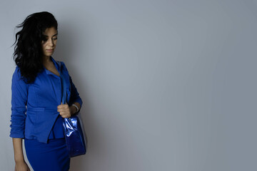A pensive young businesswoman dressed in blue on blue Monday, subject at left.