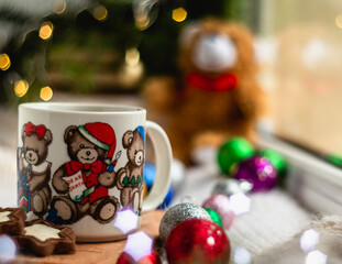 Christmas still life with a cup of hot tea with the image of bears on a blurred shiny background.