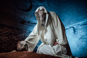 a man dressed as a plague doctor holds a human skull in his hand. costume party for Halloween. cosplay of the horseman of the apocalypse. props burning skull - obrazy, fototapety, plakaty