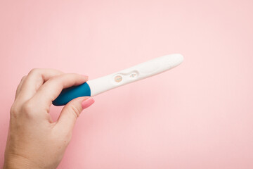 Pregnancy test in hand on a pink background . Positive test. Pregnancy copy space.