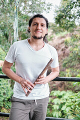 portrait of young latin man with bamboo quena flute in his hands