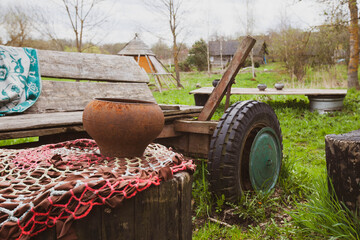 Photo of a bench, cauldron and cart on the street in the village