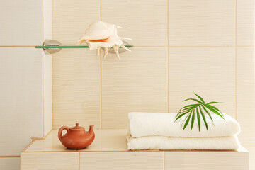 Bath towels, seashell and ceramic kettle in the bathroom interior