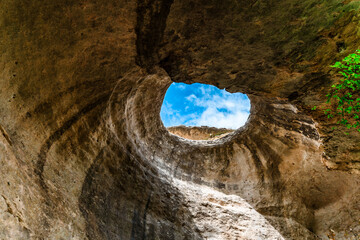  A hole from which the sun's rays and the sky are visible outside of an underground cave, an abnormal natural phenomenon in the rocks in the Crimea