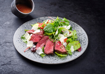 Modern style traditional fried dry aged bison beef rump steak slices with vegetable, lettuce and...