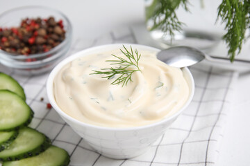Tasty creamy dill sauce in bowl on white kitchen towel, closeup