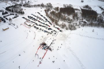 Aerial view of the ski lift at the foot of the ski slope with a crowd of skiers and snowboarders....