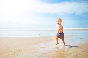 Fototapeta na wymiar Cute child boy run fast on the sand sea beach