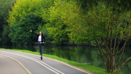 A young woman rides an electric scooter on a bike path in the park