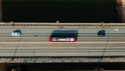 Obraz premium The modern city tram. The tramway follows the bridge over the river. A view of the tram from above.. The concept of modern urban transport