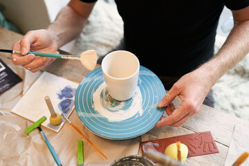 weiße Keramik bemalen, mit Pinsel und Männerhand