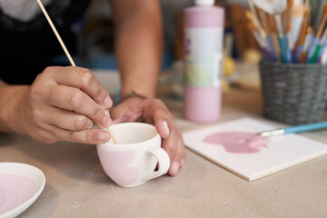 Keramik malen, weiß und rosa, mit Pinsel und Frauenhand