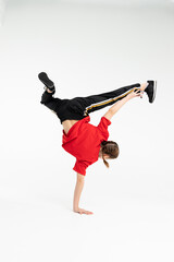 Russian b-girl break dancer in red t-shirt in white background doing stunt hand stand turning back...