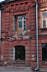 Fototapeta na wymiar Old red brick house. Wooden balcony door with peeling paint.
