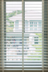 white fabric roller blinds on the plastic window with wood texture. Window with open modern horizontal white blinds indoor. White wood window blinds.