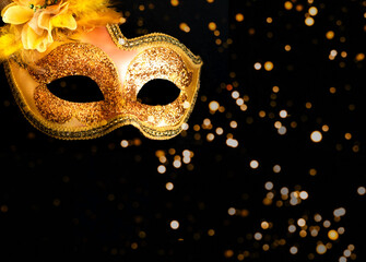 Golden Carnival mask on dark background with sparkles. Mardi Gras concept. Creative copy space