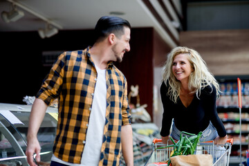 Couple in a supermarket with shopping cart while grocery shopping