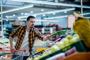 Young handsome man in a supermarket grocery shopping