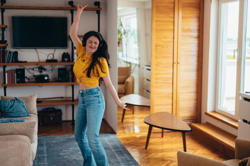 Woman dancing while listening a music on a headphones at home