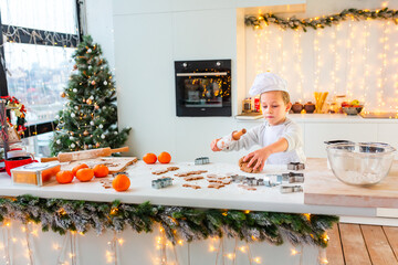 Cute little boy making gingerbread, cutting cookies of gingerbread dough.