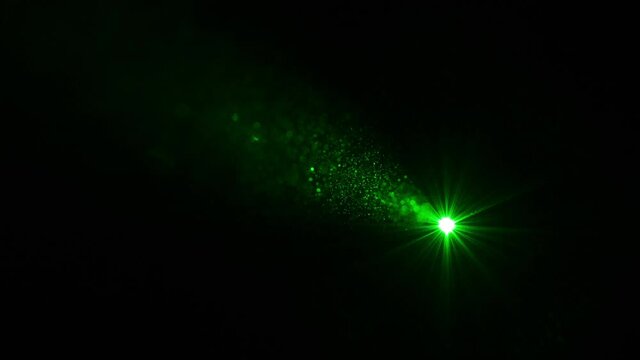The green laser ray shining on a black background. slow motion