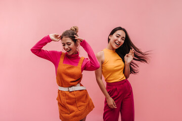 Energetic young two interracial girls dancing side by side and waving hands in studio. Models with...