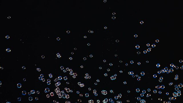The colorful soap bubbles flying on a black background. slow motion