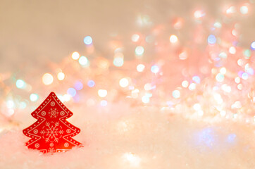 A red wooden Christmas tree with white patterns in the snow against a background of bright lights. Christmas atmosphere. Red color. Space for text. Minimalism. Soft focus.