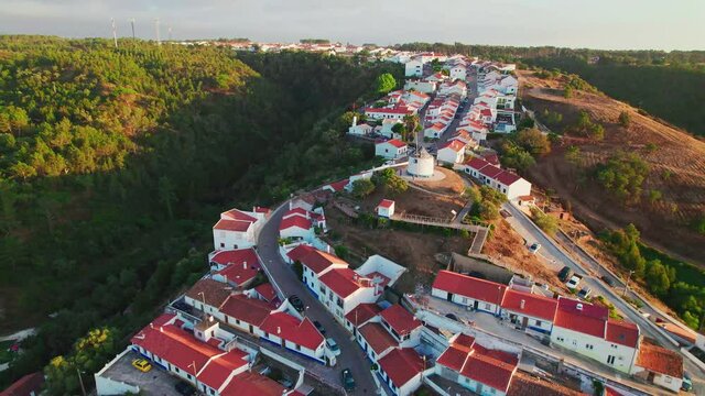 Scenic sunset over a Portuguese village with traditional colourful houses in 4K. Whitewashed traditional windmill in Odeceixe, Aljezur, Portugal, Algarve, near the Nature Park.