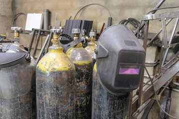 Gas cylinders for gas welding are in the workshop. The welder's mask hangs on the cylinder. Metal...