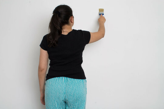 Woman paints the wall white.
