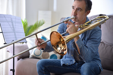 Man practicing trombone in a sofa at home