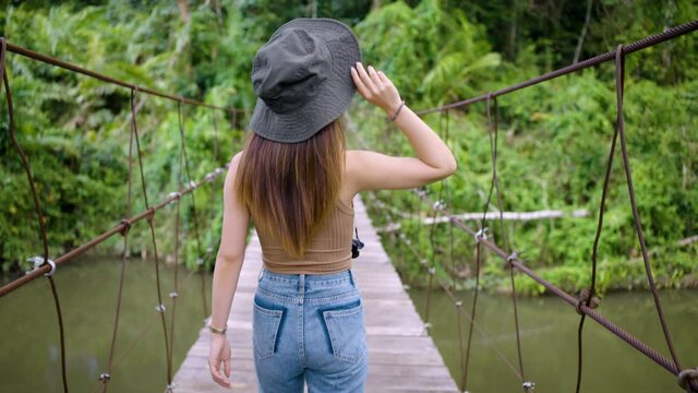 4K slow-motion footage of Young Asian woman walking on suspension bridge in jungle in Khao Yai national park in Nakhon Ratchasima. concept of Eco tourism
