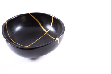 Isolated Japanese kintsugi black bowl restored with real gold , black pottery with gold cracks