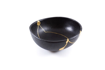 Isolated Japanese kintsugi black bowl restored with real gold , black pottery with gold cracks