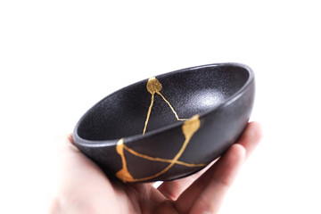 Isolated Japanese kintsugi black bowl restored with real gold , black pottery with gold cracks