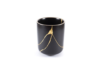 Isolated Japanese kintsugi cup restored with real gold , black pottery with gold cracks