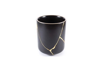 Isolated Japanese kintsugi cup restored with real gold , black pottery with gold cracks