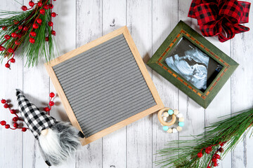Baby pregnancy birth announcement letterboard mockup. Christmas farmhouse theme styled with gift with buffalo plaid bow and farmhouse style gnomes against a white wood background.