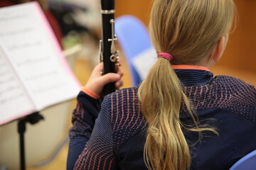 Portrait of a blonde student girl with a musical instrument clarinet sitting with notes at a lesson...