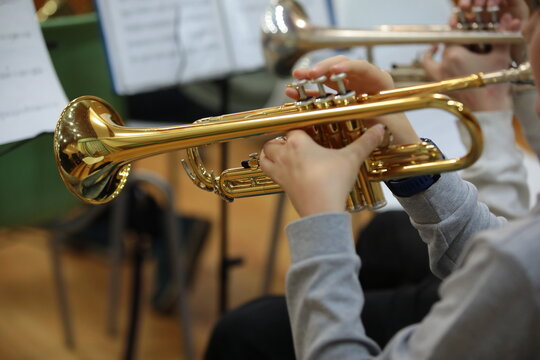 Golden trumpet in the hand of a trumpeter player playing musician.School jazz band concert background image close-up