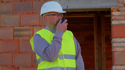 Professional builder engineer architect operate with radio walkie-talkie talking to control working...