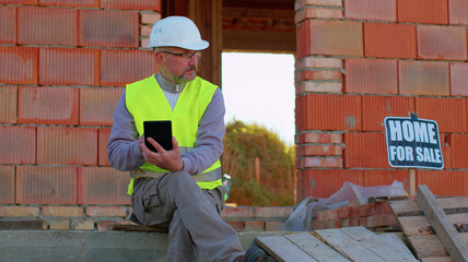 Professional builder engineer architect operate with digital tablet to control working at construction site. Foreman worker wearing hard hat, vest at building house. Business, real estate, investment