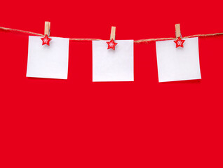 Christmas red background. Three sheets of paper with space for text on a rope. Top view, copy space